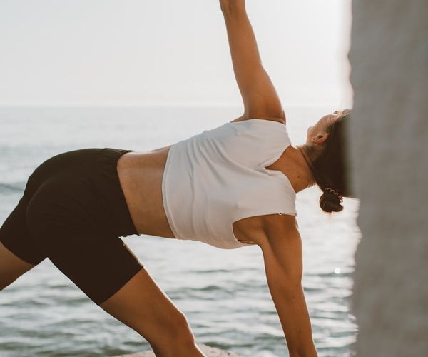 Person in a strong warrior yoga pose outdoors at sunrise.
